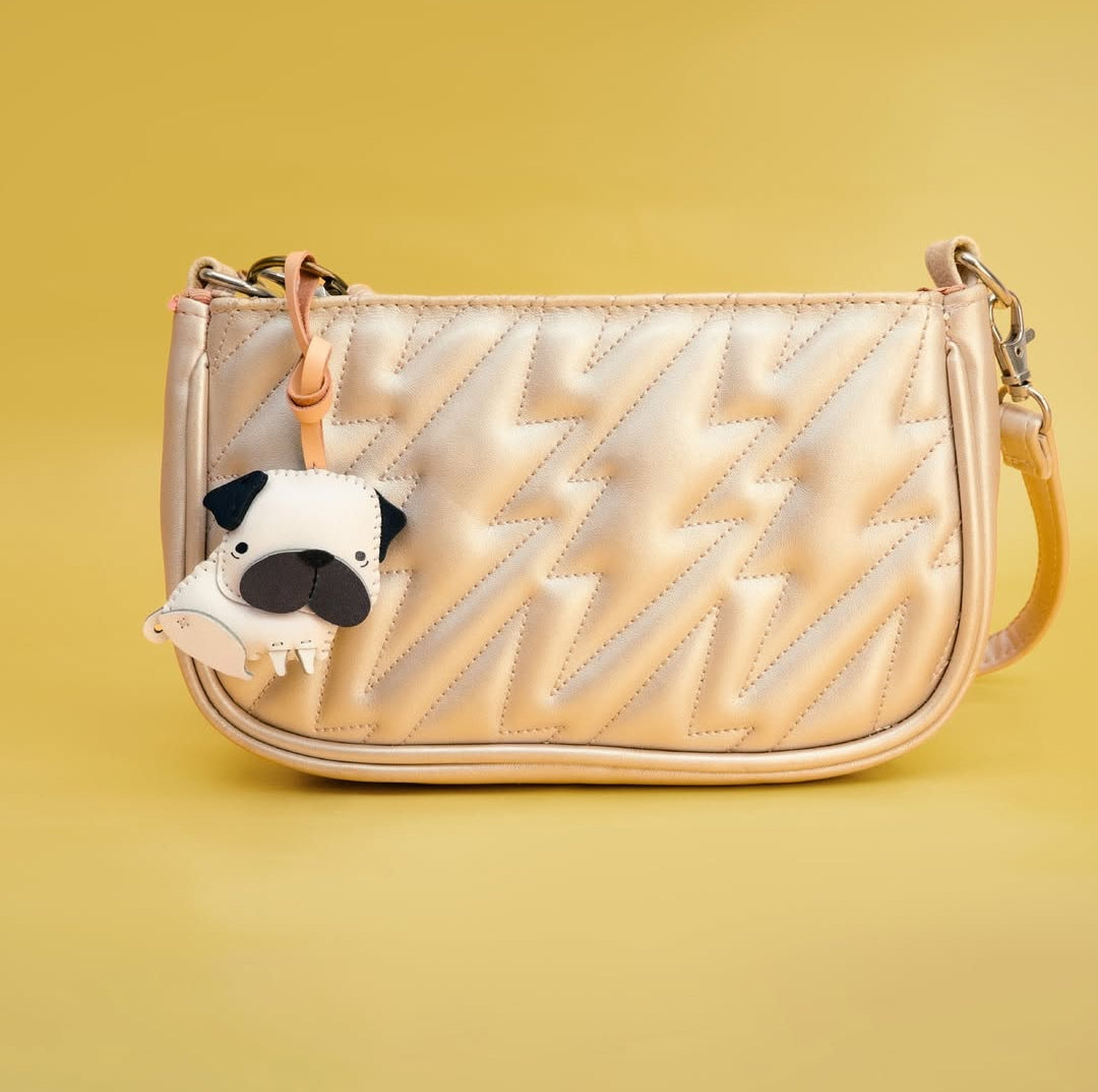 Quilted handbag with a pug-shaped charm on a yellow background