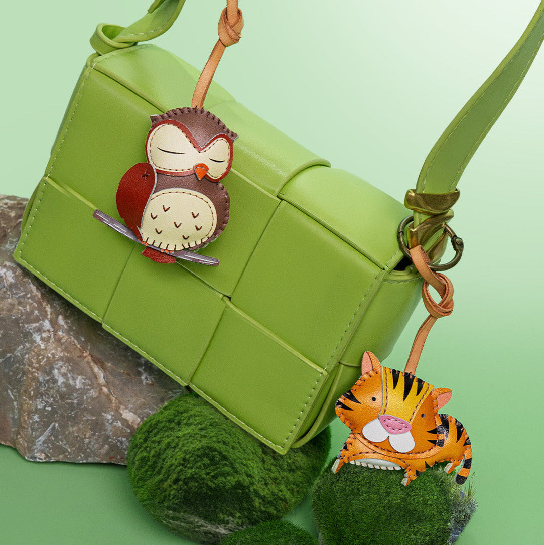 Green handbag with owl and tiger keychains on a green background