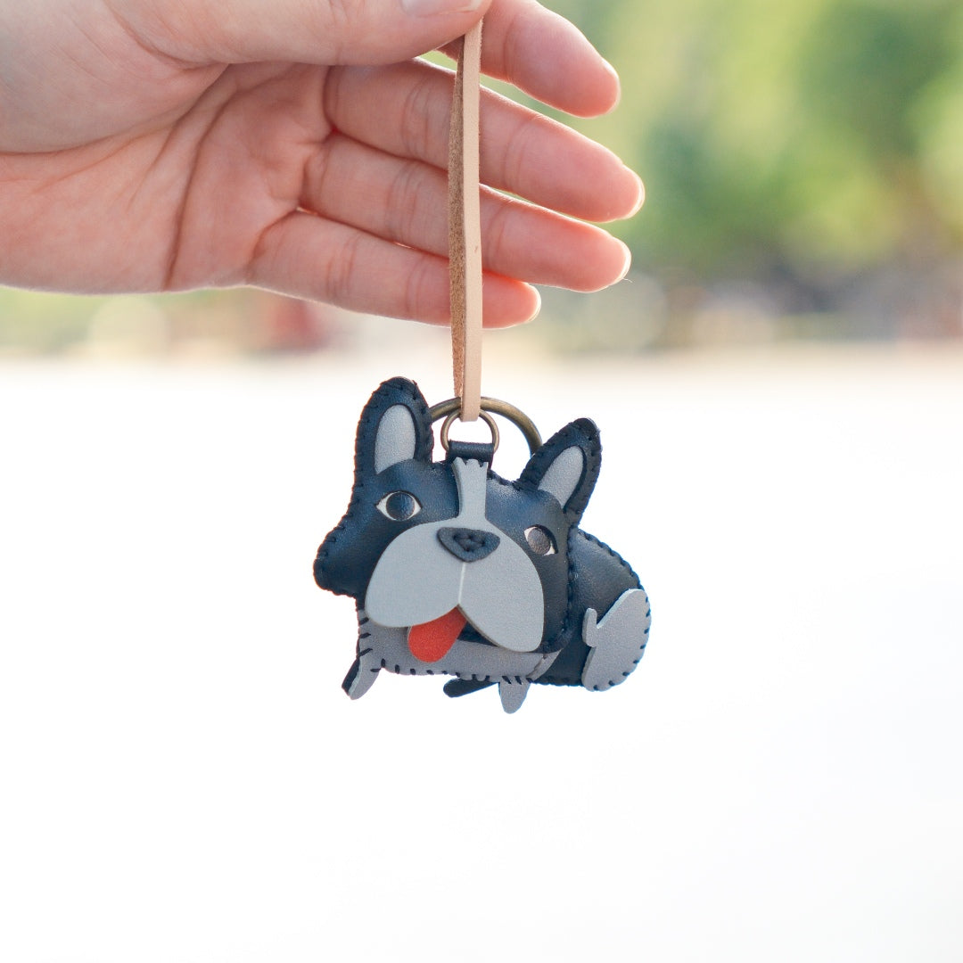 Dog-shaped keychain held by a hand against a blurred natural background