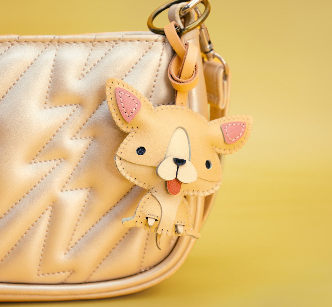Dog-shaped keychain attached to a beige quilted handbag on a yellow background