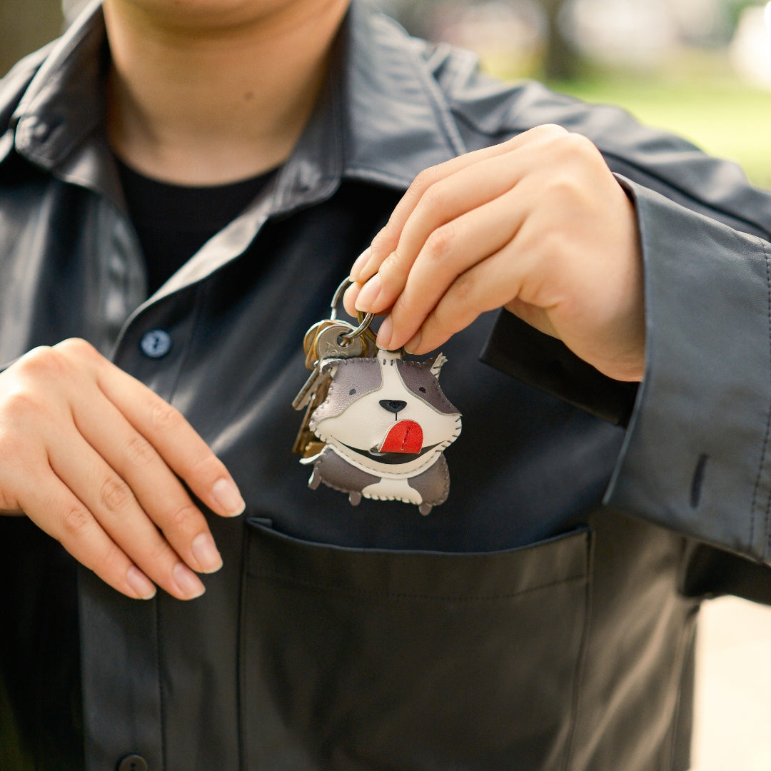 Person holding a keychain with a cartoon dog design outdoors